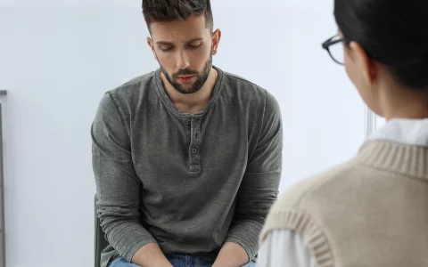 Psychotherapist working with drug addicted man indoors