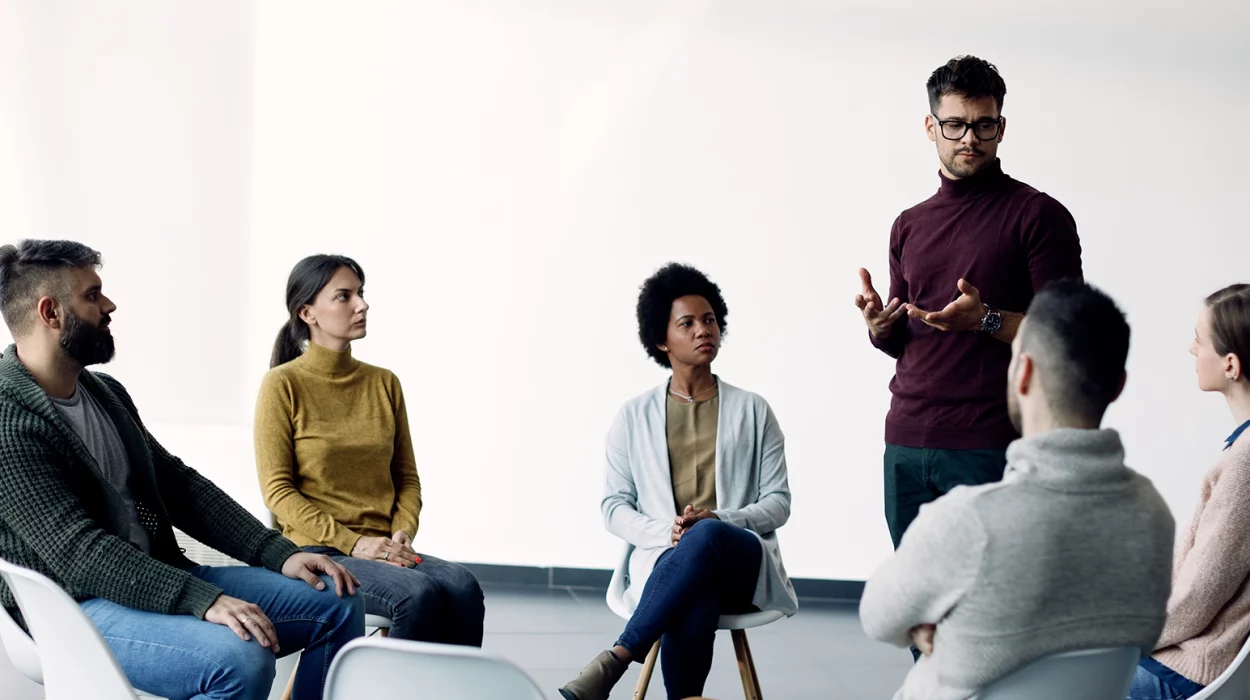 Young man sharing his problems with support group during therapy at rehab center