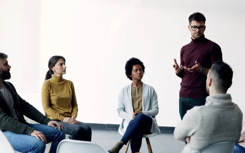 Young man sharing his problems with support group during therapy at rehab center