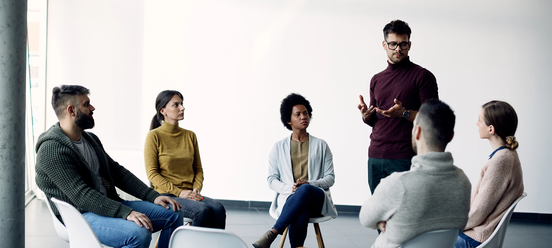 Young man sharing his problems with support group during therapy at rehab center