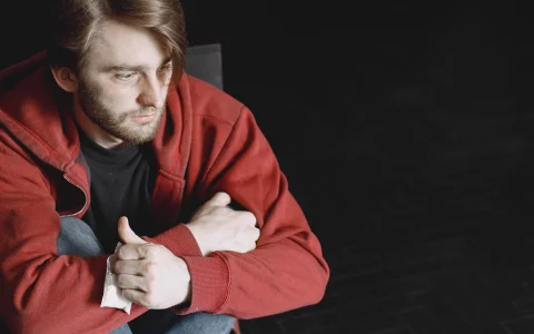 Young addicted man with cocaine packet sitting alone