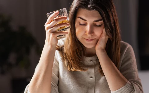 female alcoholic drinking whiskey at home