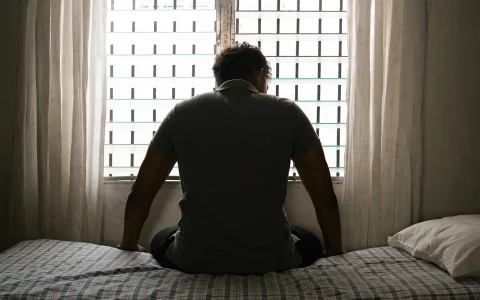 desperate man in silhouette sitting on the bed alone
